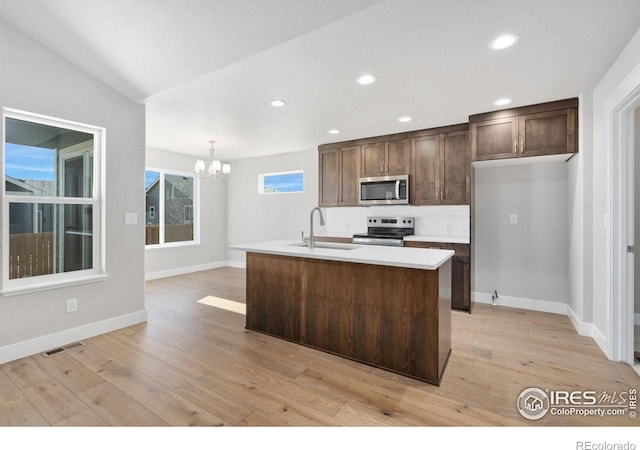 kitchen with tasteful backsplash, visible vents, appliances with stainless steel finishes, dark brown cabinets, and a sink