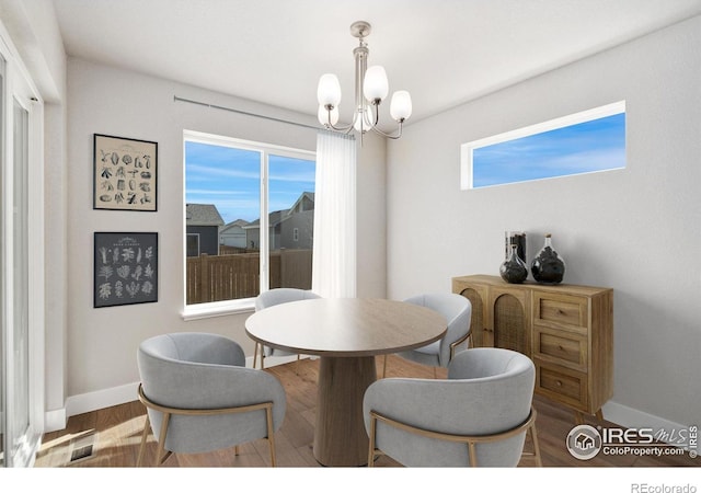 dining room with baseboards, wood finished floors, and an inviting chandelier