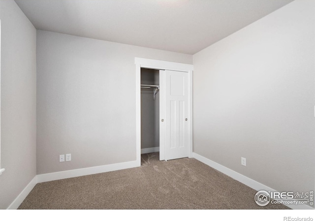 unfurnished bedroom with a closet, carpet, and baseboards