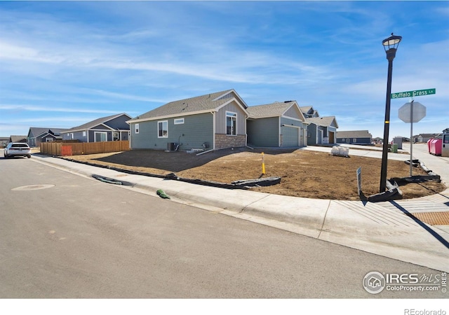 view of front of house featuring a garage, a residential view, fence, and board and batten siding