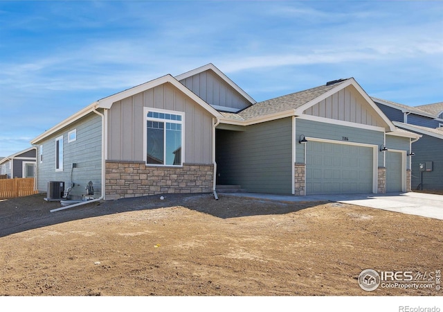 view of front of home featuring roof with shingles, concrete driveway, board and batten siding, a garage, and stone siding