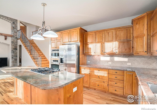 kitchen with a center island, decorative light fixtures, light hardwood / wood-style floors, and appliances with stainless steel finishes