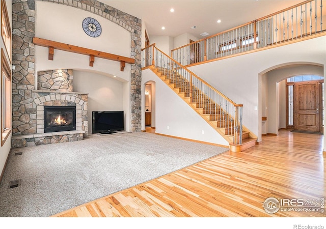 unfurnished living room with a fireplace, a towering ceiling, and wood-type flooring