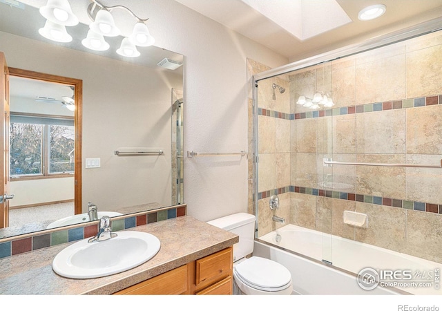 full bathroom featuring ceiling fan, vanity, bath / shower combo with glass door, and toilet