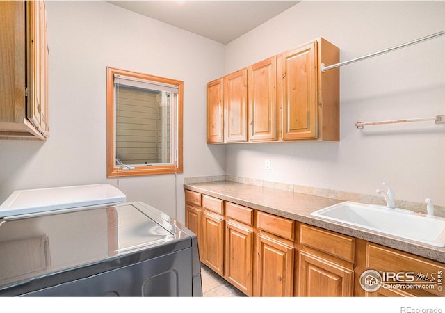 laundry area with washing machine and dryer, sink, light tile patterned floors, and cabinets