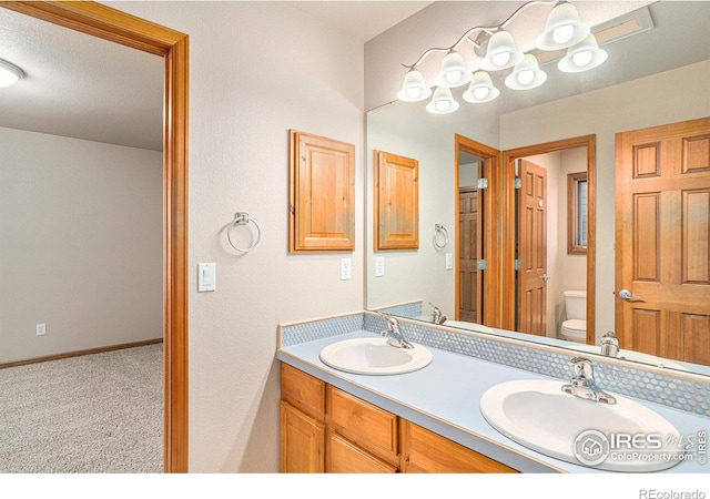 bathroom with a textured ceiling, vanity, and toilet