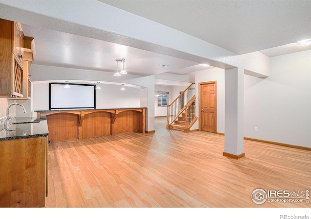 kitchen featuring dark stone counters, sink, and light hardwood / wood-style floors