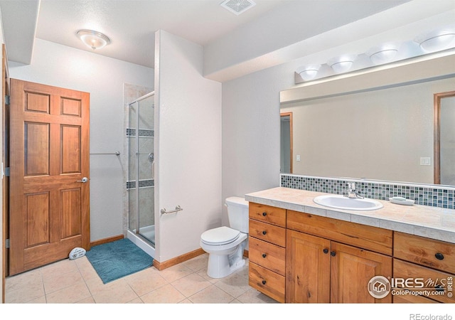 bathroom featuring tile patterned floors, vanity, toilet, and walk in shower