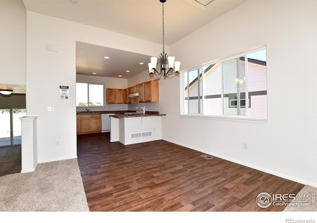 kitchen featuring dark wood-type flooring, stainless steel range oven, kitchen peninsula, white dishwasher, and decorative light fixtures