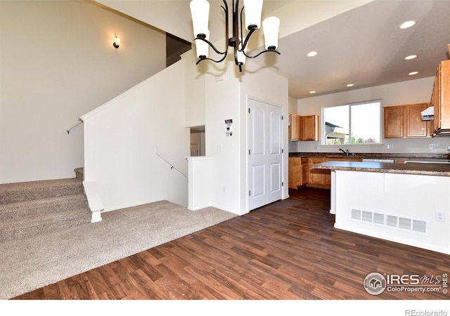 kitchen with pendant lighting, dark hardwood / wood-style floors, sink, and a notable chandelier