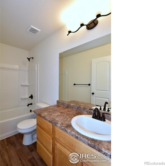 full bathroom featuring shower / bath combination, a textured ceiling, vanity, hardwood / wood-style flooring, and toilet