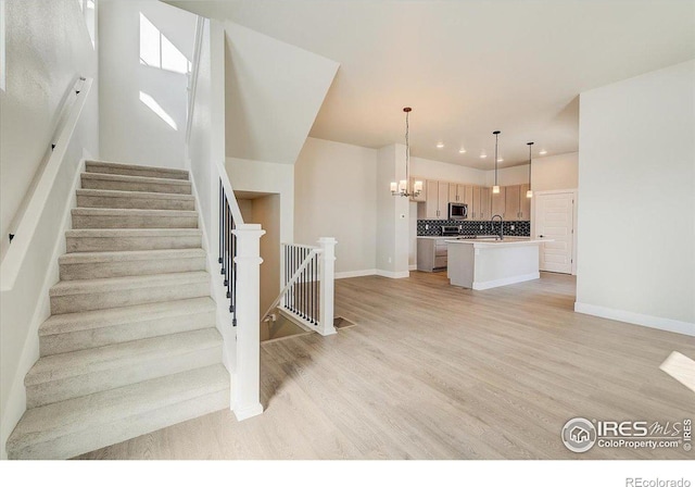 stairs with a notable chandelier, wood-type flooring, and sink