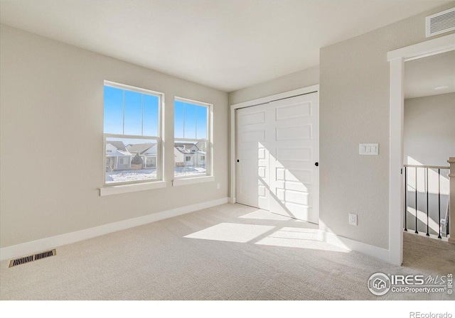 unfurnished bedroom with light carpet and a closet