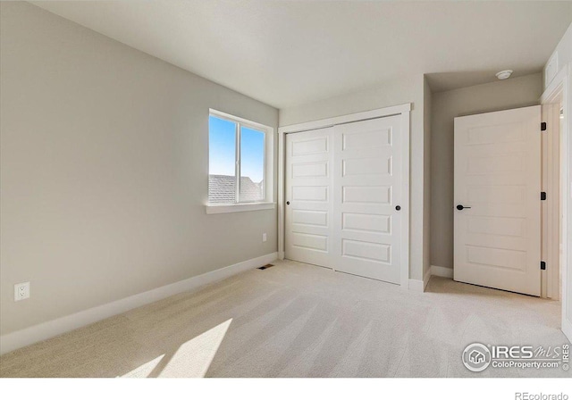 unfurnished bedroom featuring a closet and light colored carpet