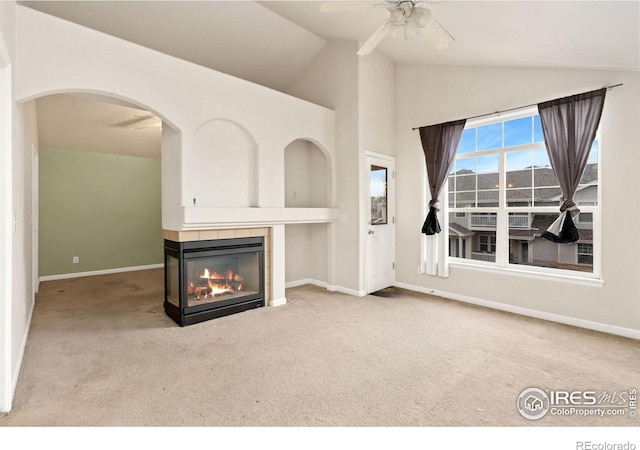 unfurnished living room featuring a multi sided fireplace, ceiling fan, light colored carpet, and vaulted ceiling