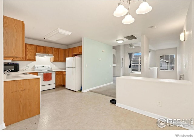 kitchen with sink, white appliances, hanging light fixtures, and an inviting chandelier