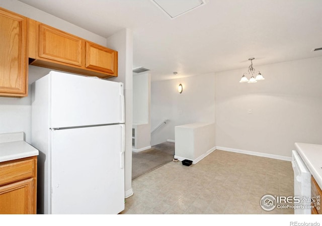 kitchen with white fridge, hanging light fixtures, and an inviting chandelier