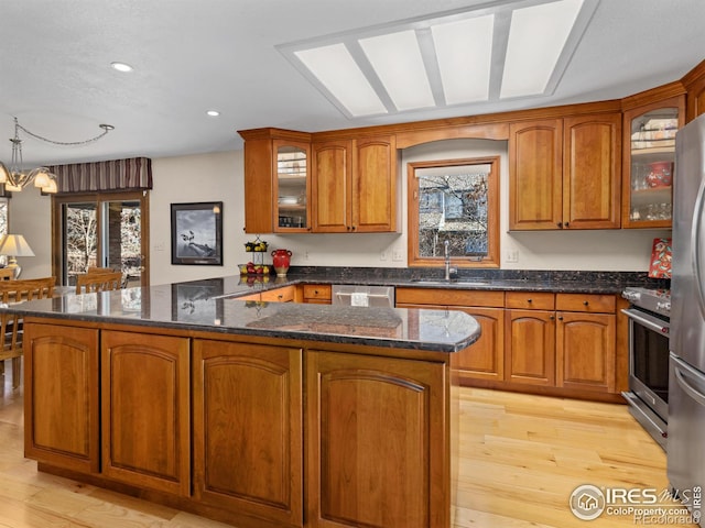 kitchen with sink, hanging light fixtures, light hardwood / wood-style flooring, kitchen peninsula, and stainless steel appliances