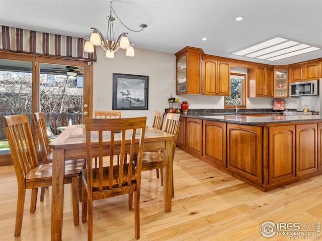 kitchen with ceiling fan with notable chandelier, a healthy amount of sunlight, light hardwood / wood-style floors, and hanging light fixtures