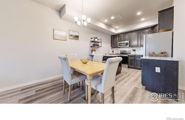 dining area with a chandelier, light hardwood / wood-style floors, and sink