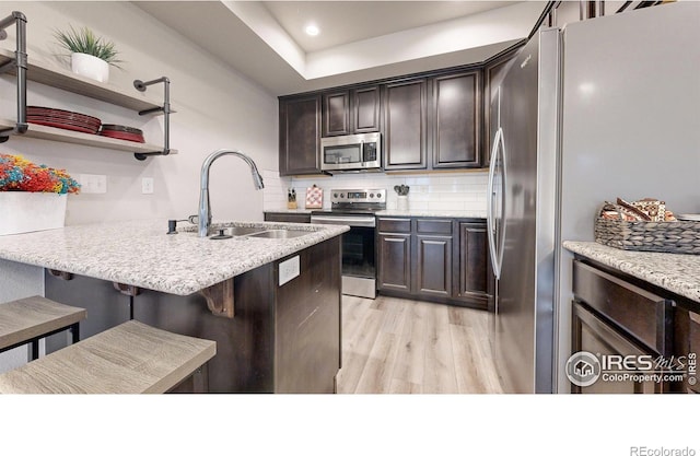 kitchen with sink, decorative backsplash, light hardwood / wood-style floors, a kitchen bar, and stainless steel appliances