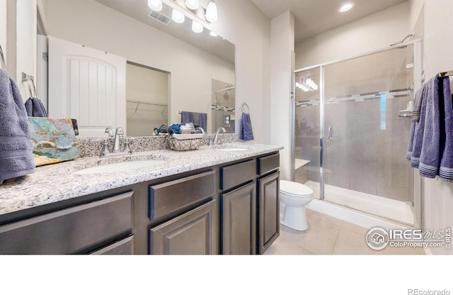 bathroom with tile patterned floors, a shower with door, vanity, and toilet