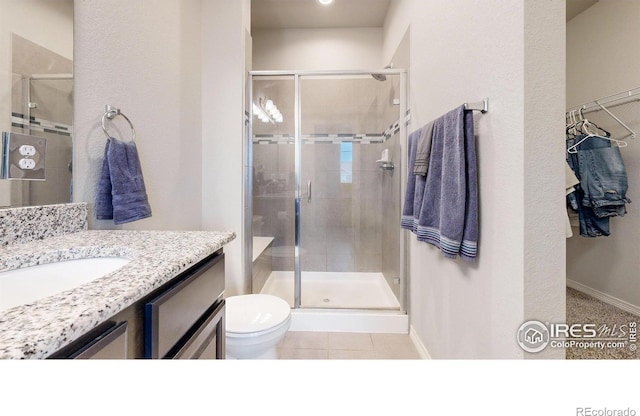 bathroom with tile patterned flooring, vanity, toilet, and walk in shower