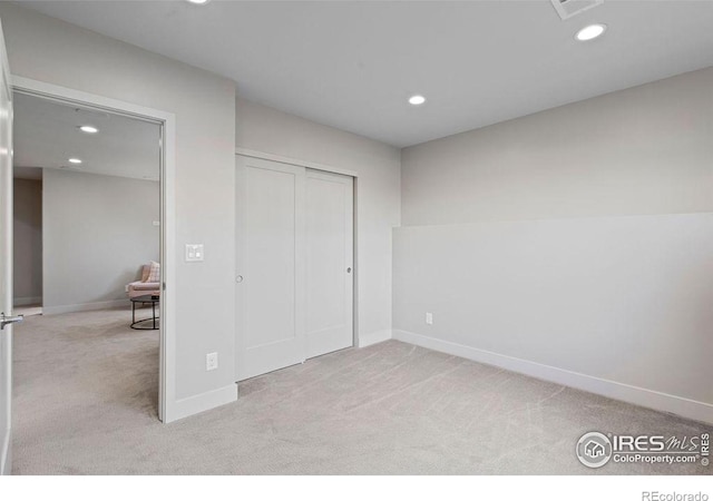 unfurnished bedroom with light carpet and a closet