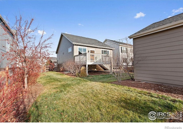 rear view of house featuring a lawn and a deck