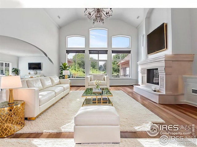 living room with an inviting chandelier, wood-type flooring, and high vaulted ceiling