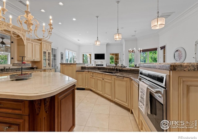 kitchen with pendant lighting, sink, light tile patterned floors, a center island, and oven