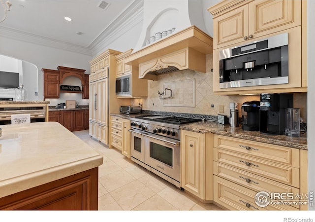 kitchen with ornamental molding, appliances with stainless steel finishes, dark stone counters, and decorative backsplash