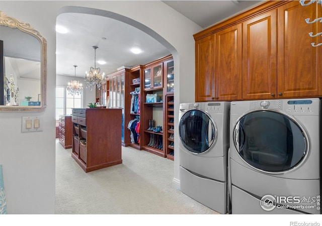 washroom with cabinets, washing machine and dryer, light colored carpet, and a notable chandelier