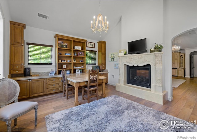 dining space featuring high vaulted ceiling, a high end fireplace, a chandelier, and light hardwood / wood-style floors