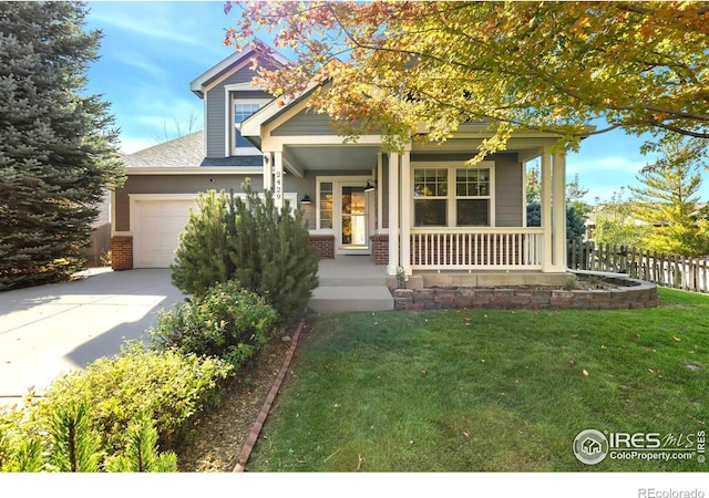 view of front of house with covered porch, a garage, and a front yard