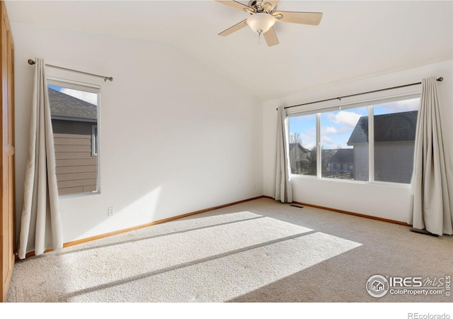 carpeted spare room featuring vaulted ceiling and ceiling fan