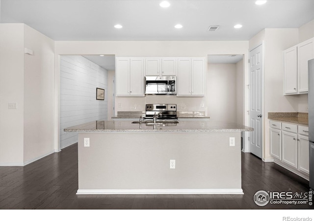 kitchen featuring a center island with sink, white cabinetry, stainless steel appliances, and dark wood-type flooring