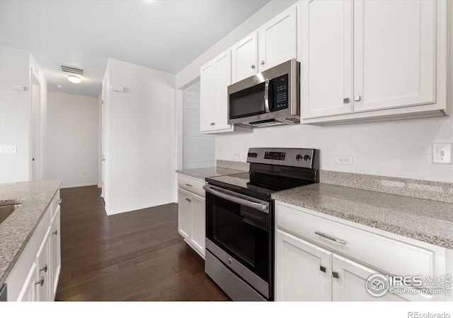 kitchen featuring white cabinets, appliances with stainless steel finishes, dark hardwood / wood-style floors, and light stone countertops