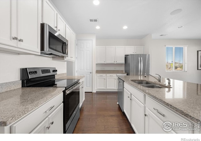 kitchen with white cabinetry, sink, stainless steel appliances, light stone counters, and dark hardwood / wood-style flooring