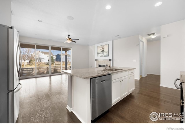 kitchen featuring light stone countertops, white cabinetry, stainless steel appliances, and a kitchen island with sink