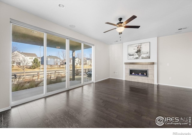 unfurnished living room with a tiled fireplace, ceiling fan, and hardwood / wood-style flooring