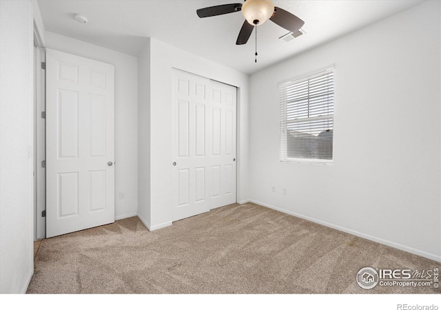 unfurnished bedroom with ceiling fan, light carpet, and a closet