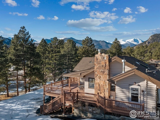 snow covered rear of property with a deck with mountain view