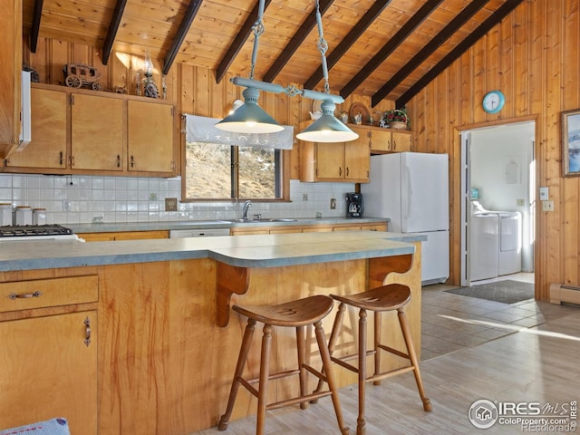 kitchen with wood walls, white appliances, backsplash, light hardwood / wood-style flooring, and separate washer and dryer