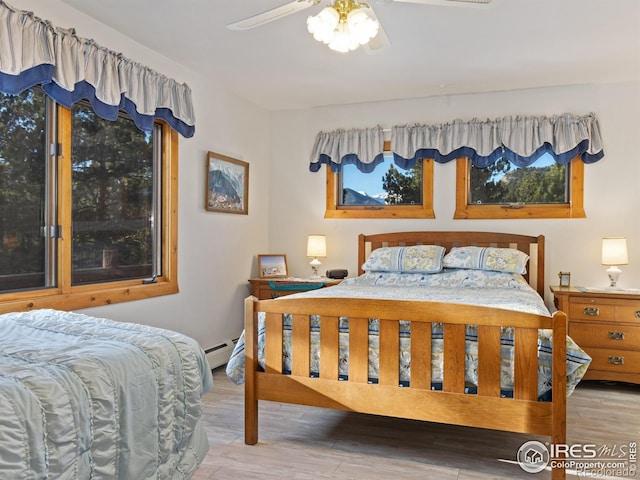 bedroom featuring ceiling fan, light wood-type flooring, and baseboard heating