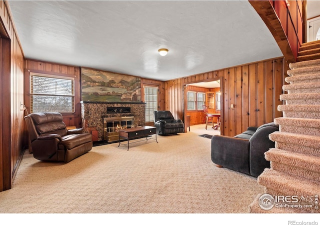 carpeted living room featuring wood walls and a fireplace