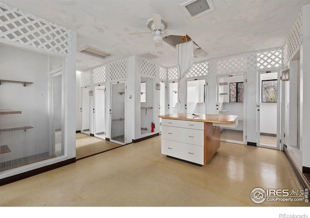 kitchen with white cabinetry, ceiling fan, and wood counters