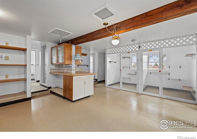 kitchen with beam ceiling, kitchen peninsula, white cabinets, and hanging light fixtures