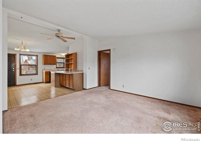 unfurnished living room featuring ceiling fan with notable chandelier, a textured ceiling, and light colored carpet