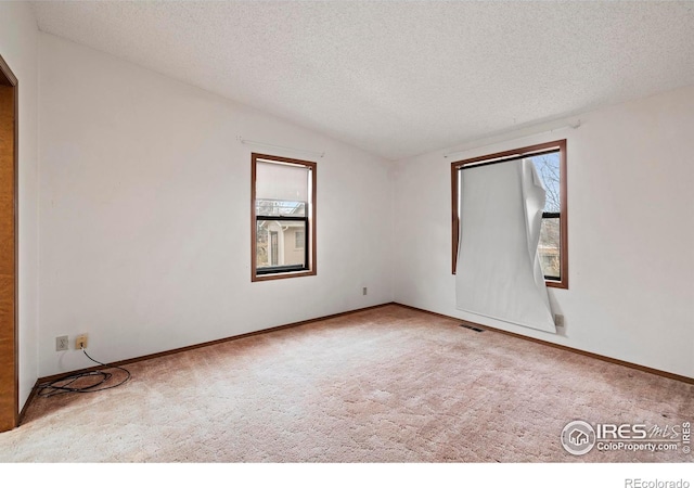 carpeted spare room with vaulted ceiling and a textured ceiling